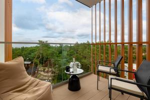 a balcony with a table and chairs and a large window at Pinea617 Seaview in Pobierowo