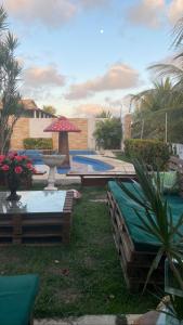 einen Hinterhof mit einem Pool mit einem Tisch und einem Sonnenschirm in der Unterkunft Pousada Paradise in Canoa Quebrada