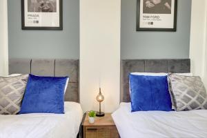 two beds with blue pillows in a bedroom at A Gem in Central Hull - Sleeps 6 in Hull