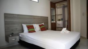 una camera da letto con un grande letto bianco con testiera in legno di D Río Apartamentos a Ríohacha