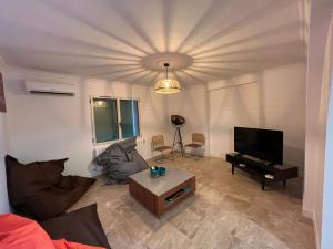 een woonkamer met een bank en een flatscreen-tv bij Mas Grenadine, magnifique villa du Piémont Cévenol in Sauve