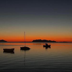 trois bateaux assis dans l'eau au coucher du soleil dans l'établissement MUREX, à Marsala