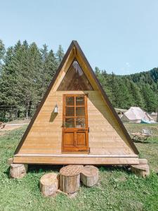 een klein houten huis met een groep houtblokken bij Hobo Camping in Courmayeur