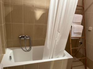 uma casa de banho com banheira e cortina de chuveiro em Porto Rafti Holiday Apartment em Porto Rafti