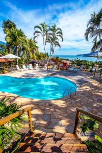 een zwembad in een resort met palmbomen en de oceaan bij Pousada Altamira in Ilhabela