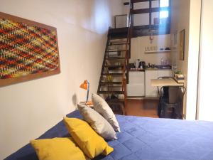 a bedroom with a bed with yellow pillows and a kitchen at Azules de Abril in Yerba Buena