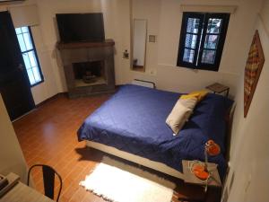 1 dormitorio con cama azul y chimenea en Azules de Abril en Yerba Buena