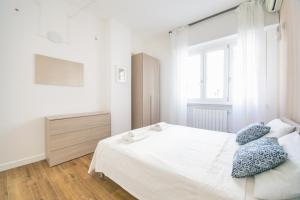 una camera da letto con un letto bianco con cuscini blu di Vacanze Romane Apartment a Roma
