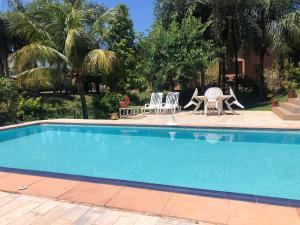 a swimming pool with two chairs and a table and chairs at Flats Naturando's in Buritama