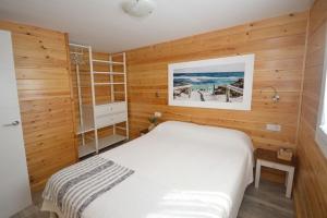1 dormitorio con cama blanca y paredes de madera en Casa Nordica cerca del mar en El Palmar