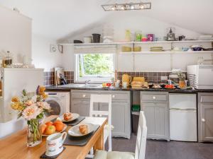 a kitchen with white cabinets and a table with fruit on it at The Shepherd's Hut in Aberdyfi