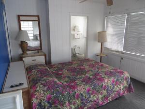 a bedroom with a bed and a mirror and a window at Royal Palms Motel in Stuart