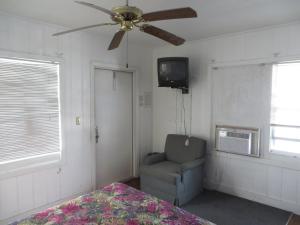 a bedroom with a ceiling fan and a chair and a television at Royal Palms Motel in Stuart