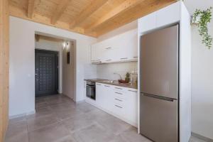 cocina con armarios blancos y nevera en Olive Zen Villa, en Akrotiri