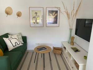 a living room with a green couch and a tv at Casa Violeta - Golf & tenis in Estepona