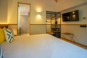 1 dormitorio con 1 cama blanca grande y TV en Sercotel El Balcón de la Bahía Suites en Santander