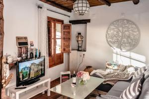sala de estar con sofá y TV en La Casita del Árbol Blanco en Bubión