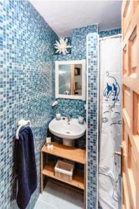 baño con paredes de azulejos azules y lavabo en La Casita del Árbol Blanco en Bubión