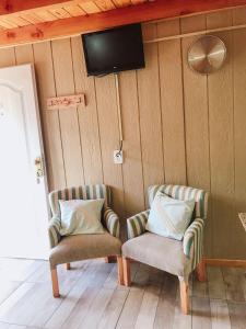 two chairs in a room with a tv on the wall at Encanto Patagónico in El Bolsón
