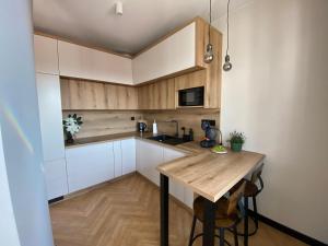 cocina con armarios de madera y mesa de madera en Apartament Nowe Zatorze 92, en Olsztyn