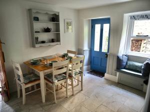 une salle à manger avec une table, des chaises et une porte bleue dans l'établissement Rose Cottage, à Matlock