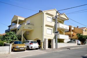 a yellow building with cars parked in front of it at Apartment Luka in Zadar