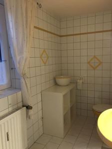 ein weiß gefliestes Bad mit einem Waschbecken und einem WC in der Unterkunft Haus Dany in Raeren