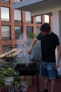 a man is cooking food on a grill at La Familia Hostel - Parque Poblado in Medellín