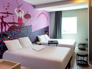 ein Hotelzimmer mit 2 Betten und einer rosa Wand in der Unterkunft Ibis Styles Merida Galerias in Mérida