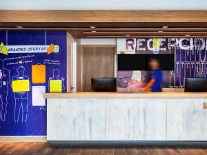 a lobby with a reception counter with a tv at ibis budget Aguascalientes Norte in Aguascalientes