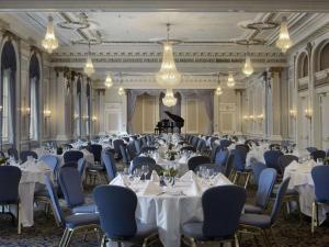 a banquet hall with tables and chairs and a piano at Fairmont Palliser in Calgary