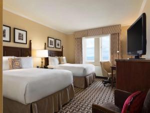 a hotel room with two beds and a flat screen tv at Fairmont Le Manoir Richelieu in La Malbaie