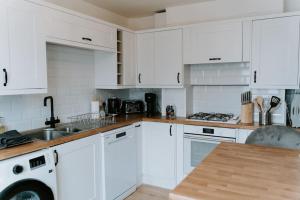 a white kitchen with white cabinets and a sink at Bluebell cottage Branston Lincoln in Branston