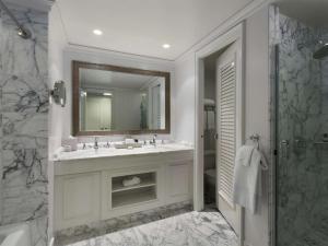 ein Bad mit einem Waschbecken, einem Spiegel und einer Dusche in der Unterkunft Fairmont Orchid in Waikoloa
