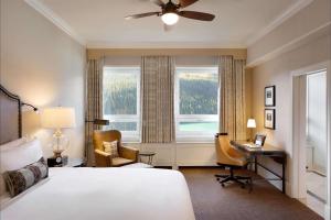 a bedroom with a bed and a desk and a window at Fairmont Château Lake Louise in Lake Louise