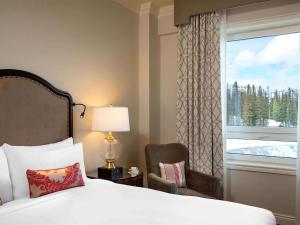 1 dormitorio con 1 cama, 1 silla y 1 ventana en Fairmont Château Lake Louise, en Lago Louise