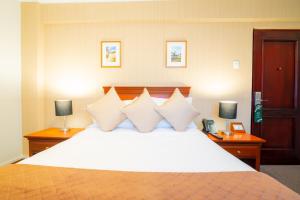 a bedroom with a large white bed with two lamps at El Tumi Hotel in Huaraz +34 photos