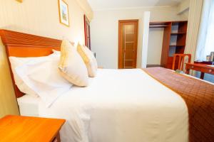 a bedroom with a white bed and a wooden table at El Tumi Hotel in Huaraz