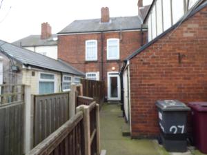 a brick house with a fence and a trash can at Station House in Shirebrook
