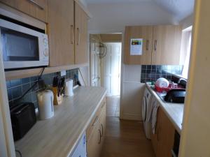 a small kitchen with wooden cabinets and a microwave at Station House in Shirebrook