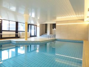 una grande piscina con piastrelle blu in un edificio di Glamory Winterberg Ferienwohnung Pool Sauna Wifi 6 Personen near Lift Balkon PS4 a Winterberg