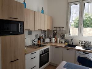 a kitchen with wooden cabinets and a sink and a microwave at Brest : Beau T1 en centre ville in Brest