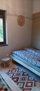 a bedroom with a bed and a table and a rug at Domek Zielenina in Mierzeszyn