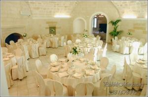 una habitación con mesas blancas, sillas blancas y registradora en Agriturismo Casale San Giovanni, en Salice Salentino