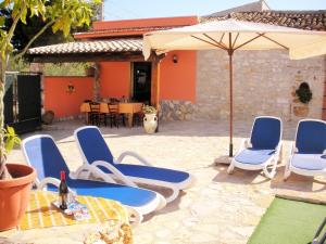 un grupo de sillas y una sombrilla en un patio en Villa Nuccia Oasi di relax con piscina, en Castellammare del Golfo