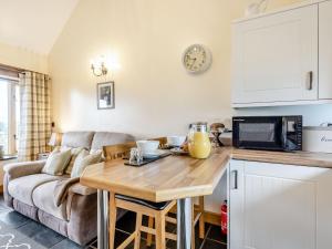 eine Küche und ein Wohnzimmer mit einem Sofa und einem Tisch in der Unterkunft The Granary in Llanfair Caereinion
