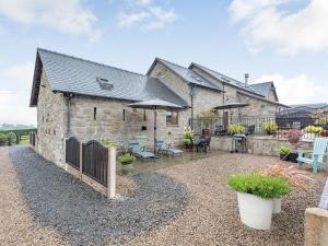 a stone cottage with an outdoor patio with umbrellas at The Granary in Llanfair Caereinion