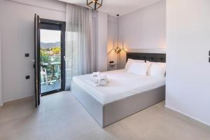 a white bedroom with a large bed and a window at Athos Veranda in Sarti