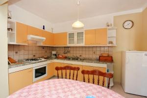 a kitchen with a table and a clock on the wall at Apartments with a parking space Kampor, Rab - 4972 in Kampor