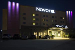 a large building with a neon sign on the side of it at Novotel Milano Malpensa Aeroporto in Cardano al Campo